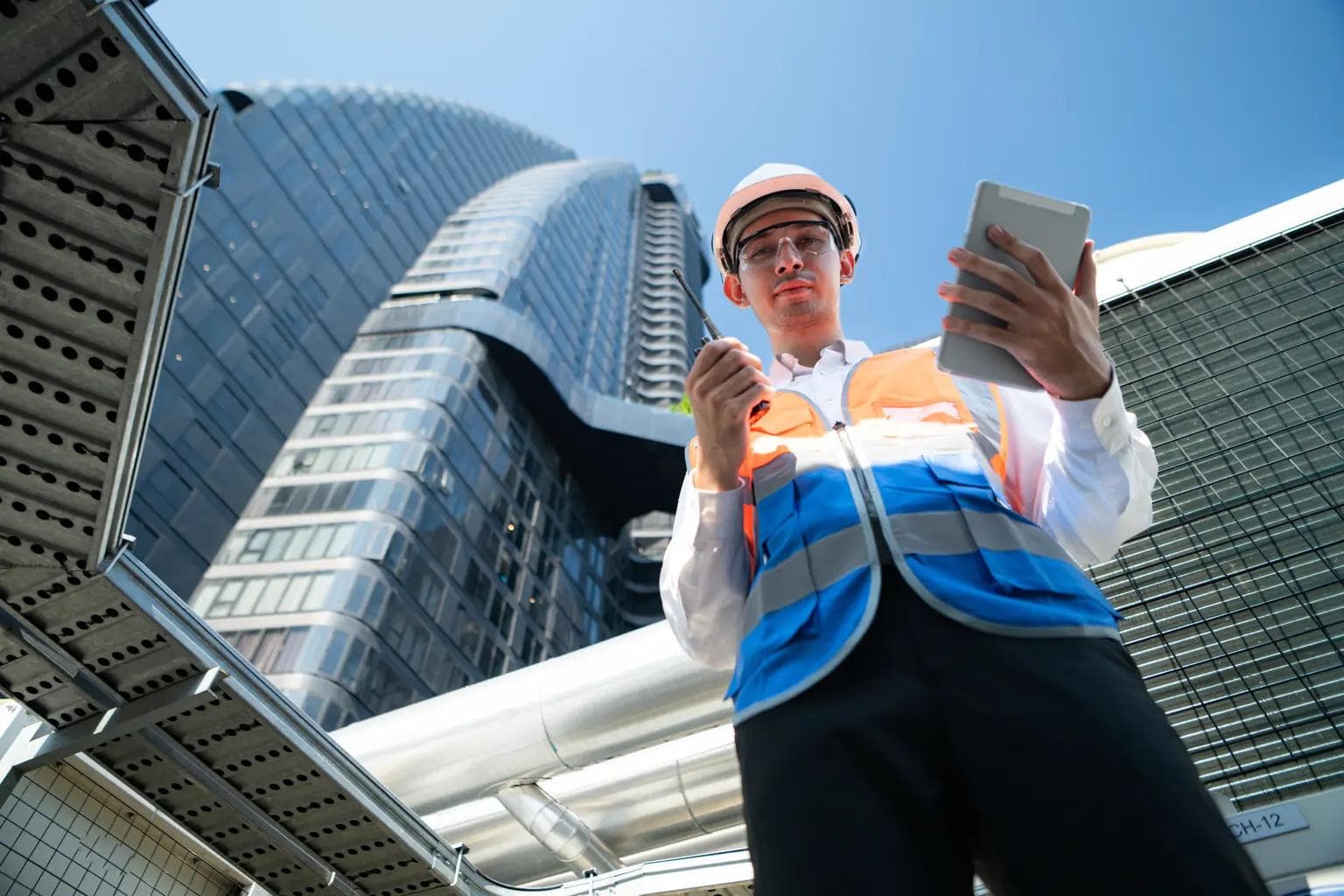 A professional pest control technician wearing a safety helmet and high-visibility vest inspecting a commercial building exterior with a tablet and inspection equipment in Sydney, Australia.